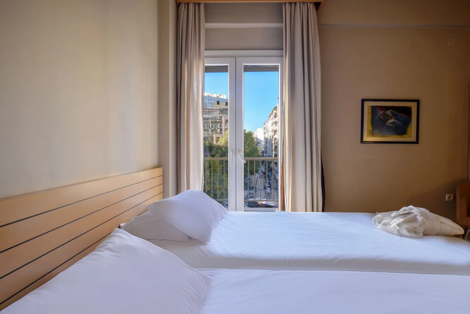 The bright light city view rooms at Astoria Hotel Thessaloniki offer a serene yet vibrant retreat, combining modern elegance with natural charm. Large windows bathe the space in abundant natural light, showcasing stunning views of Thessaloniki's live